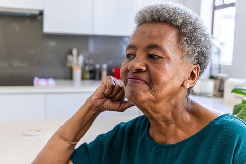 Senior african american woman resting at kitchen counter, reflecting portrait