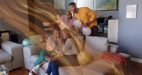 Friends Taking Selfie on Sofa During Casual Home Celebration With Balloons and Drinks