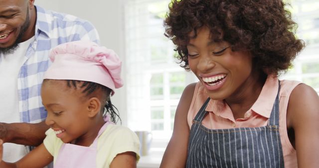 Family baking together in kitchen wearing aprons and smiles - Download Free Stock Images Pikwizard.com