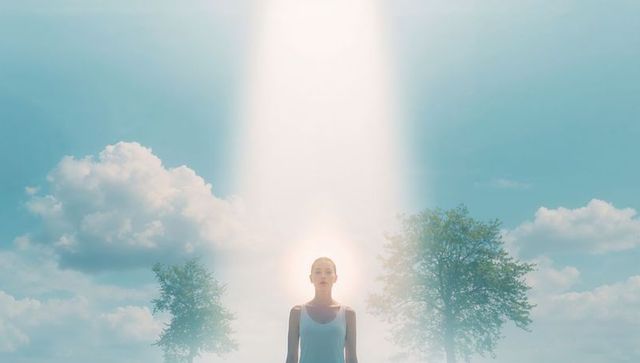 Ethereal woman bathed in vertical light beam between trees, surreal outdoor portrait