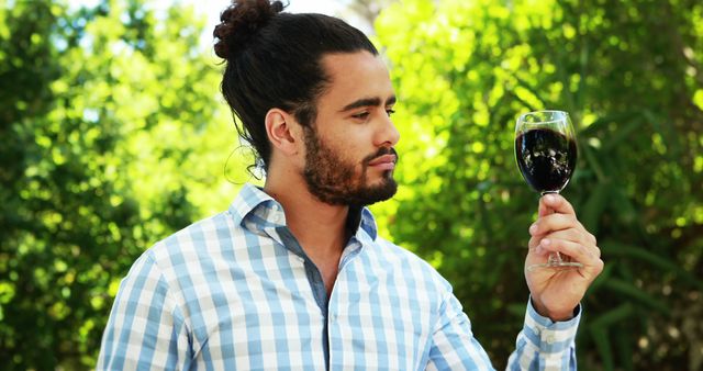 Man in Checkered Shirt Observing Red Wine in Glass Outdoors - Download Free Stock Images Pikwizard.com