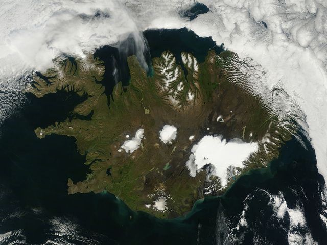 A true-color image taken by NASA's Terra satellite on August 22, 2014, shows Iceland in summer with visible vegetation, snow-capped northern peaks, and significant glaciers, including the Vatnajökull Glacier. The rugged landscape holds notable geographical features such as Iceland's highest mountain, Hvannadalshnjúkur, and evidence of volcanic activity under Bardarbunga. This image can be useful for educational materials, environmental studies, geography lessons, and illustrating volcanic and glacial regions.