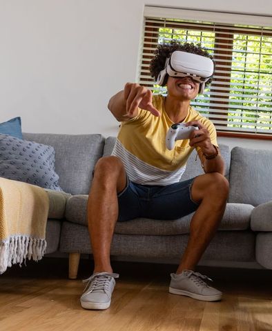 Young man playing immersive vr game on couch with wireless controller