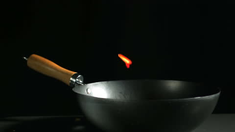 Sliced Red Pepper Falling into Wok with Black Background