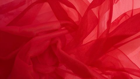 Crimson organza flowing in translucent layers with backlit folds for luxe texture