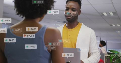 Colleague holding laptop receiving digital notifications in modern open office collaboration