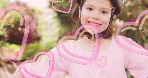 Smiling child with bike helmet and pink hearts overlay