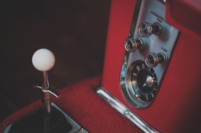 Close-up shot of a vintage car interior showcasing gear shift and dashboard controls. Ideal for use in themes related to classic vehicles, automotive parts, driving, and nostalgia. Can be used in blogs, articles, and ad campaigns focusing on transportation, vintage items, and retro aesthetics.