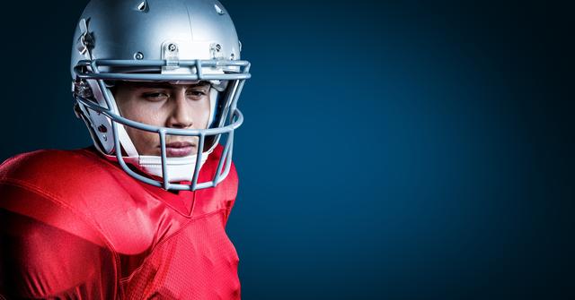 This image shows a thoughtful American football player wearing a red jersey and helmet against a blue background. It can be used for sports-related articles, motivational posters, athletic training materials, or advertisements for sports equipment.