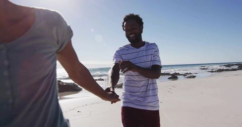 Romantic Couple Strolling Along Sunlit Beach Holding Hands