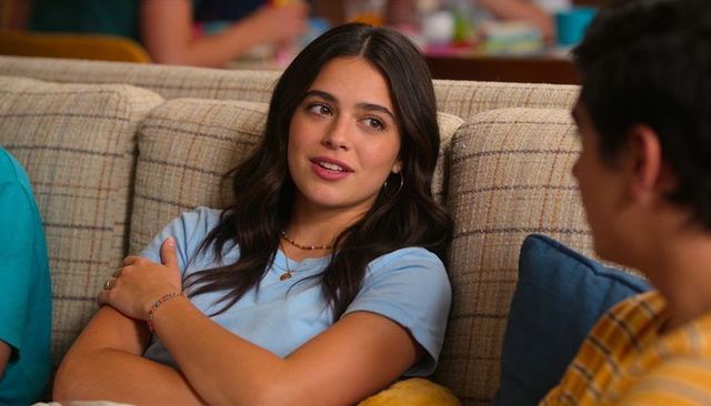 Teen girl lounging on plaid couch in light blue tee smiling and chatting in casual hangout