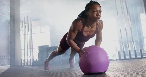 Female Athlete Doing Push-ups with Medicine Ball in Gym