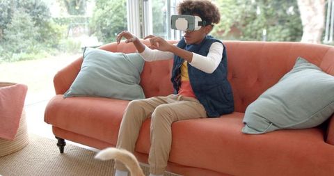 Youth immersed in virtual reality at home on cozy couch
