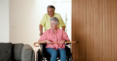 Caring senior lesbian couple with wheelchair and cane