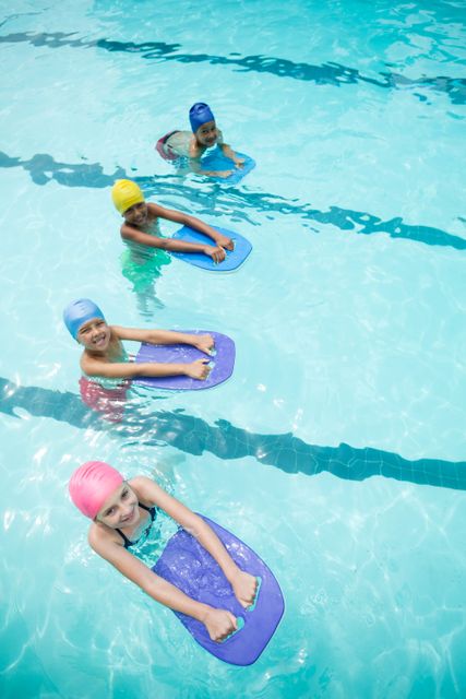 High angle view of children using kickboard while swimming in pool