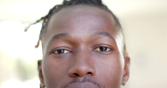 This close-up portrays an African American man with dreadlocks in natural daylight, capturing his serious and introspective expression. Use this for diversity representation in promotional materials, social media content, or artistic projects showcasing detailed human features and natural beauty.