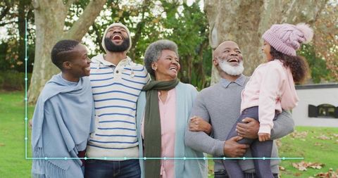 Multigenerational family laughing and hugging in autumn park, grandparents with child