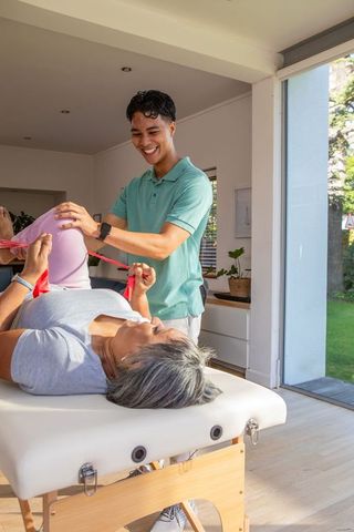 Physiotherapist assisting senior woman with exercise band therapy