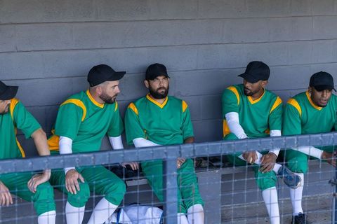 Baseball team sitting in dugout reacting to digital stats overlay on rail for strategy