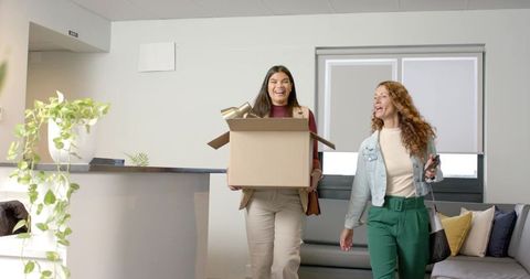 Diverse Coworkers Arriving at Office Reception with Cardboard Box