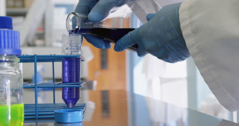 Scientist Pouring Liquid into Test Tubes in Laboratory