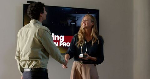 Businesswoman celebrating success with award handshake in modern office