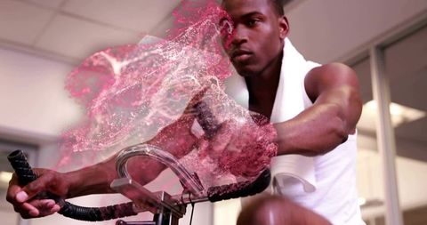 Focused athlete pedaling indoor spin bike with neon pink particle motion overlay