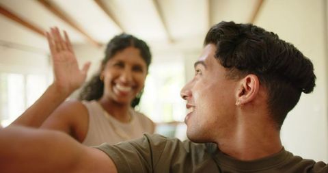 Sunlit african american couple sharing high-five and selfie in cozy living room