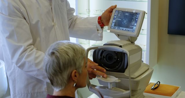 A middle-aged Caucasian healthcare professional operates an eye examination machine on a senior patient, with copy space. Advanced medical equipment aids in accurate diagnosis and treatment of eye conditions.