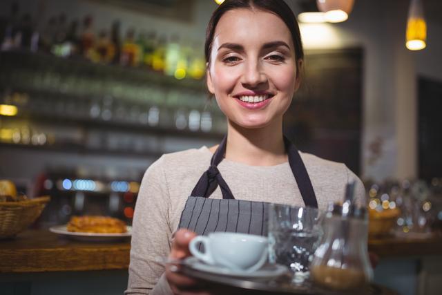 Portrait of waitress holding cup of coffee in cafÃ©