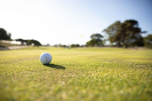 This image captures a close-up view of a golf ball on a well-maintained golf course on a sunny day. Ideal for use in sports and leisure publications, promoting outdoor activities, healthy lifestyles, and golfing events. Perfect for websites, blogs, and advertisements related to golf, sports equipment, and recreational activities.