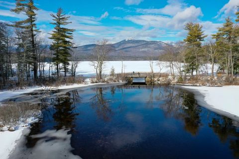 Snowy Mountain Lake with Wooden Footbridge Reflecting Blue Sky and Pine Trees