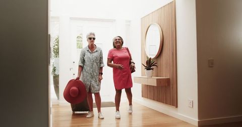 Senior lesbian couple entering hotel with baggage for vacation