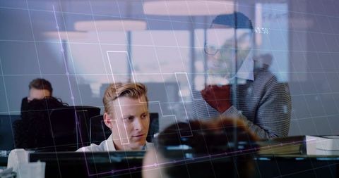 Collaborating over digital dashboards on monitors in sunlit open-plan office