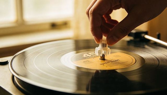 Placing 45 rpm adapter on vinyl record closeup on sunlit turntable
