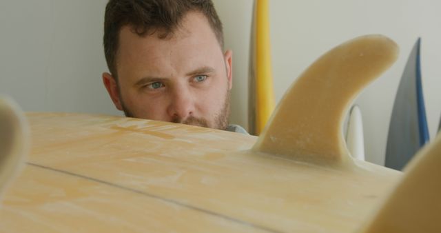 Man Heartfelty Inspecting Surfboard Fins in Workshop - Download Free Stock Images Pikwizard.com