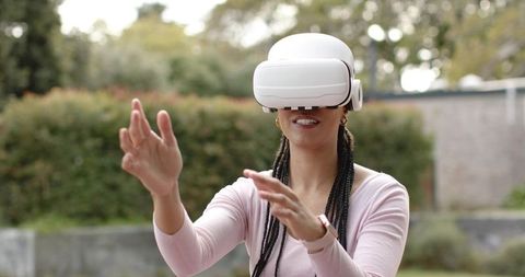 Young woman experiencing virtual reality outdoors wearing white vr headset and smartwatch