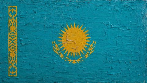 Weathered kazakhstan flag mural on textured turquoise wall with golden sun emblem