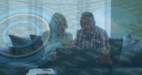 Senior couple with laptop amidst digital hologram