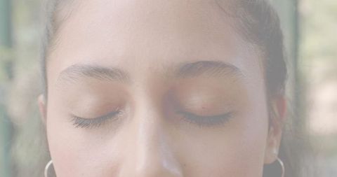 Adult woman closing eyes in serene garden closeup with soft focus and hoop earrings