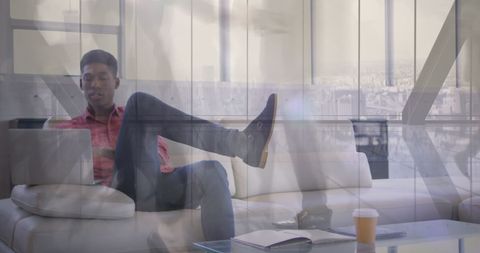 Young Man Relaxing on Sofa with Laptop and Coffee