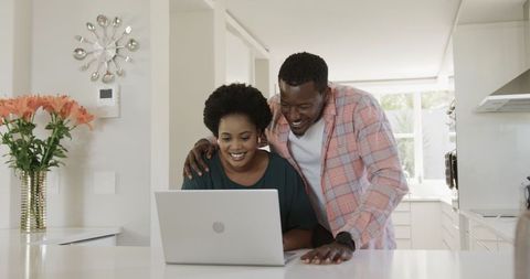 Happy couple using laptop in modern kitchen for technology and relationship bonds