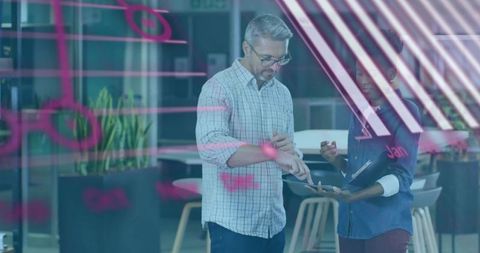 Collaborative team reviewing tablet and brainstorming on glass wall notes using stylus