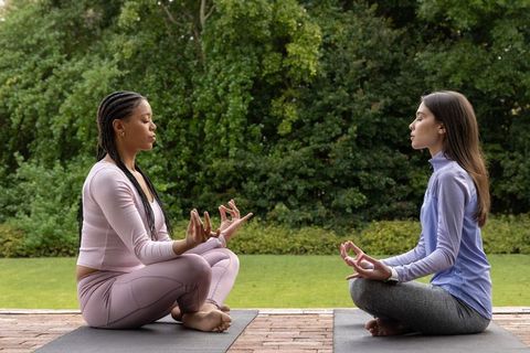 Diverse women meditating on yoga mats outdoors practicing mindfulness and breathing