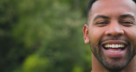 Joyful man smiling amidst lush green foliage
