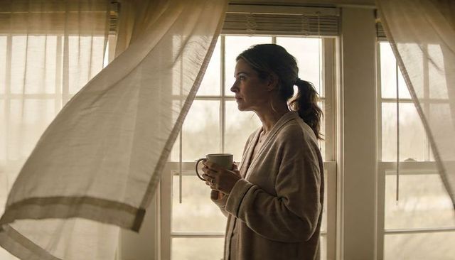 Morning contemplation at window holding mug woman in robe soft sunlight sheer curtains