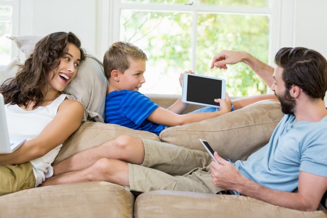 Parents and son using a laptop, tablet and phone at home