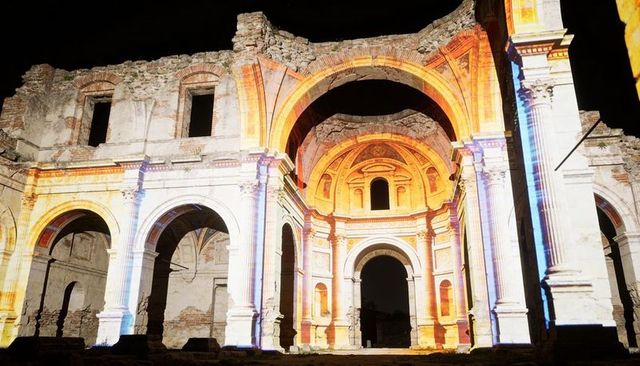 Ancient church ruins illuminating with colorful projection mapping on arched stone facade