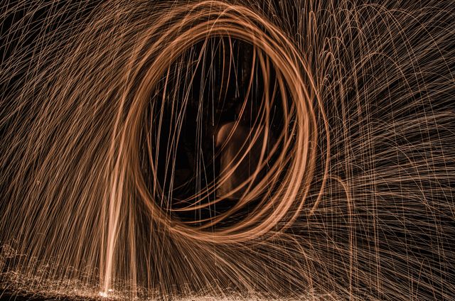 This captivating visual features an abstract light painting created through the long exposure technique, capturing vibrant sparks in motion. Perfect for use in artistic designs, backgrounds, wallpapers, creative projects, or anything requiring dynamic and mesmerizing imagery.