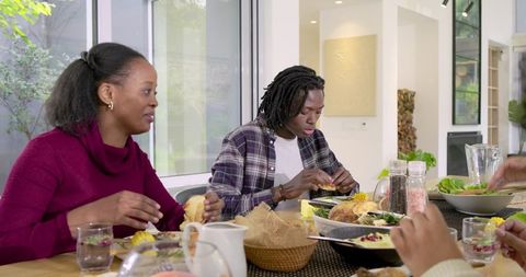 African American family sharing relaxed homemade dinner in bright modern dining room